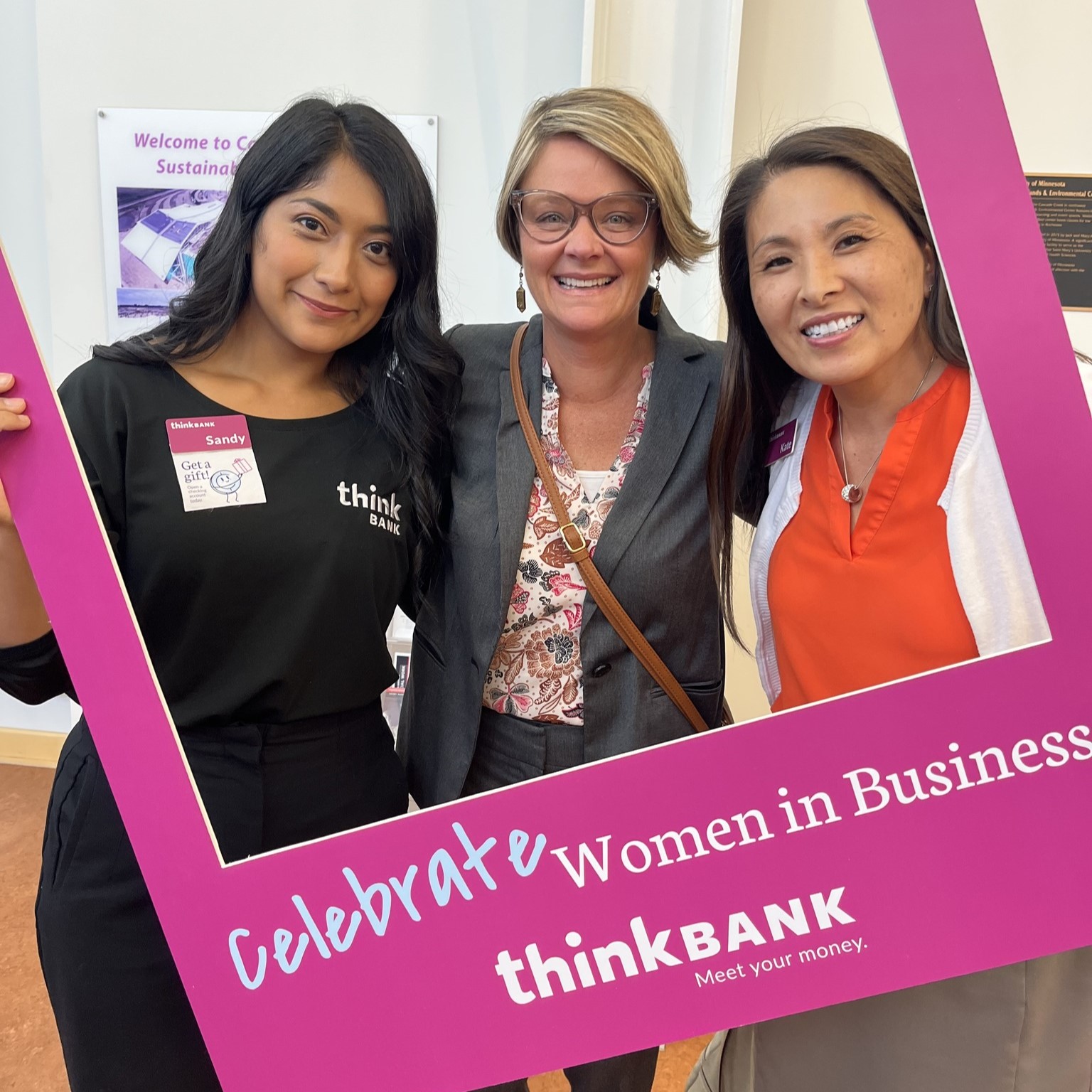 Think Bank employees holding a celebrate women in business sign.
