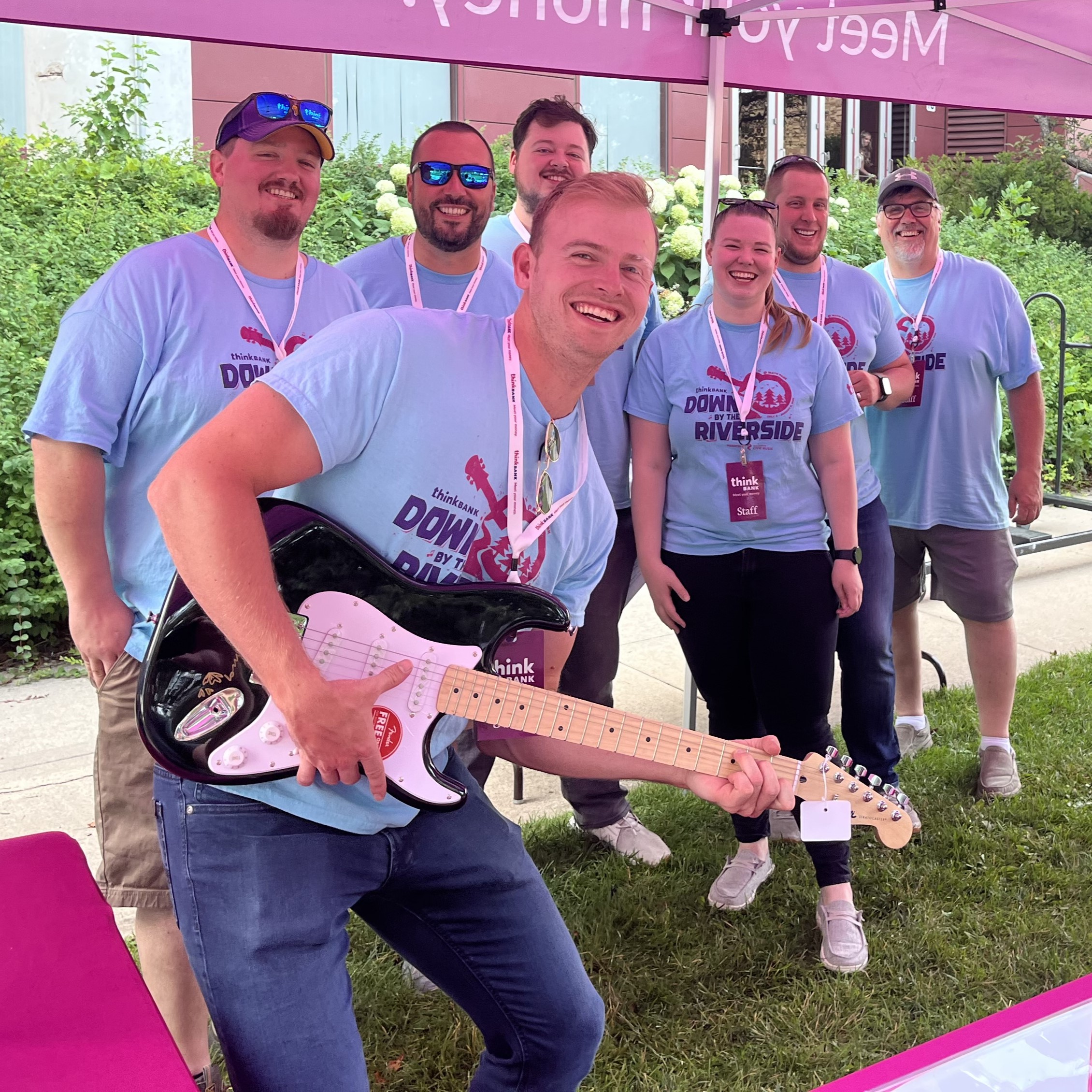 Think Bank employees with the giveaway guitar at Down by the Riverside Series concert.