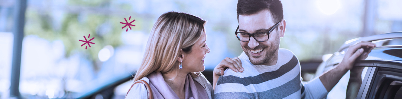 A couple smiling at each other as they shop for a new vehicle.