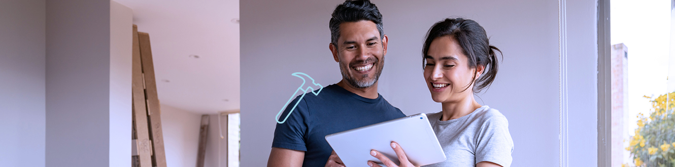 A couple smiling and looking at their home improvement plans