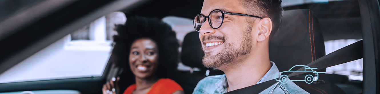 A couple sitting in a car and smiling.