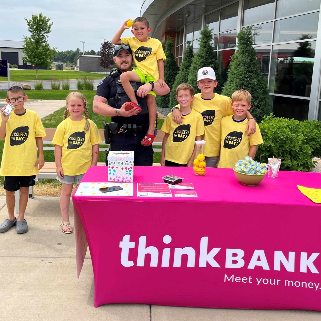 Kids standing behind a table wearing Lemonade Day t-shirts.