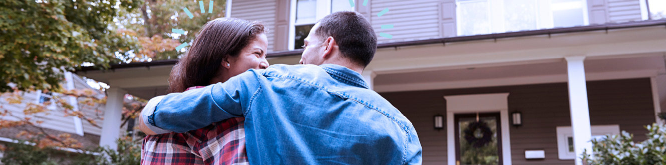 A couple walking towards their new home with similes on their faces.